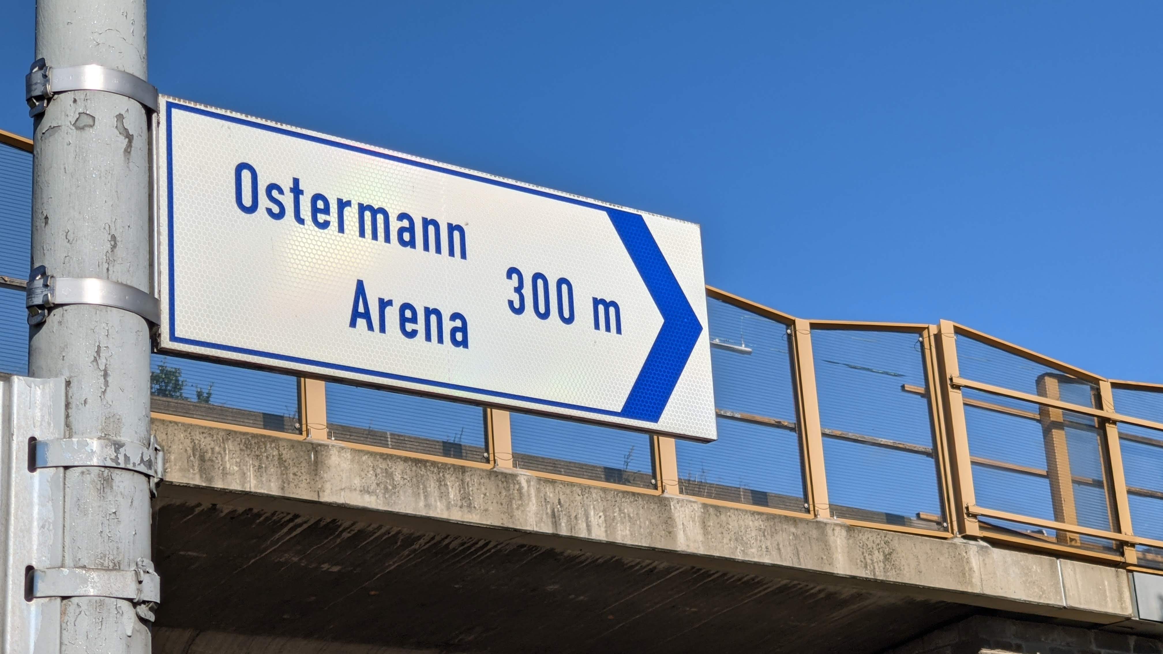 Ein Wegweiser mit dem Hinweis, in welcher Richtung es zur Ostermann-Arena geht und dass es noch 300 Meter bis dahin sind.