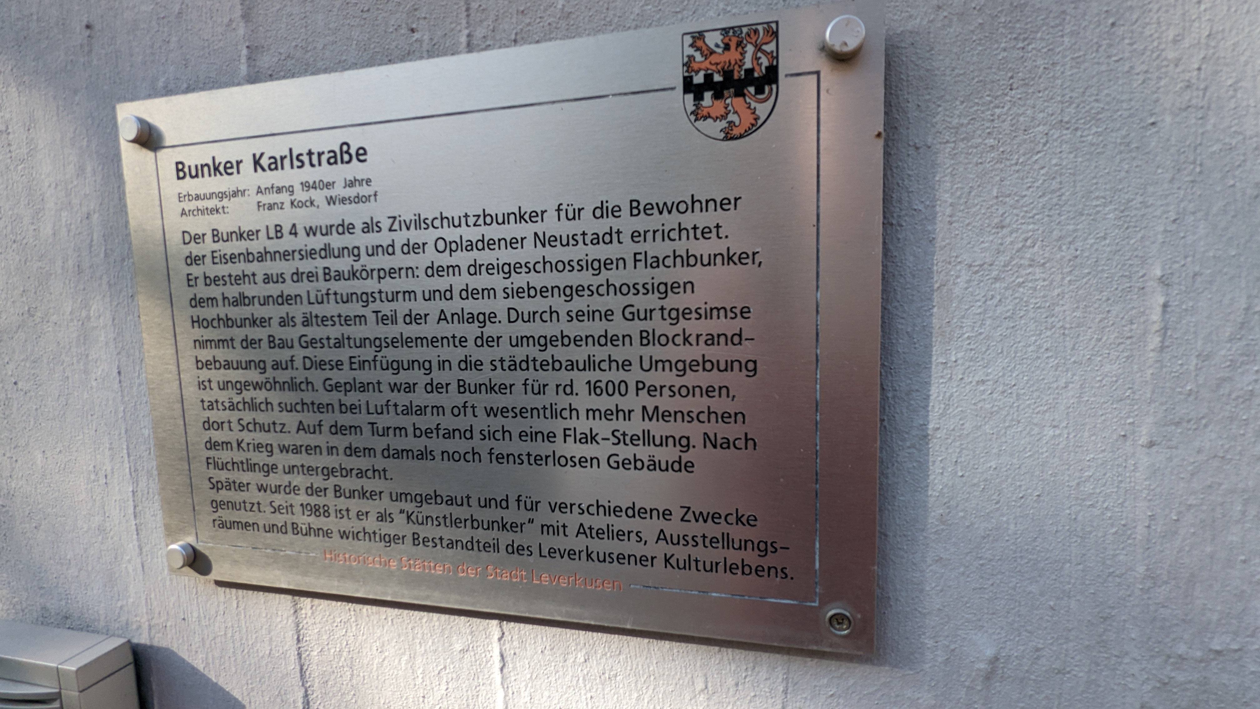 Dieses Schild befindet sich am Künstlerbunker in der Karlstraße. Es erklärt die Geschichte des Bunkers. Es ist ein Teil der Schilder, die "Historische Städten der Stadt Leverkusen" erklären.